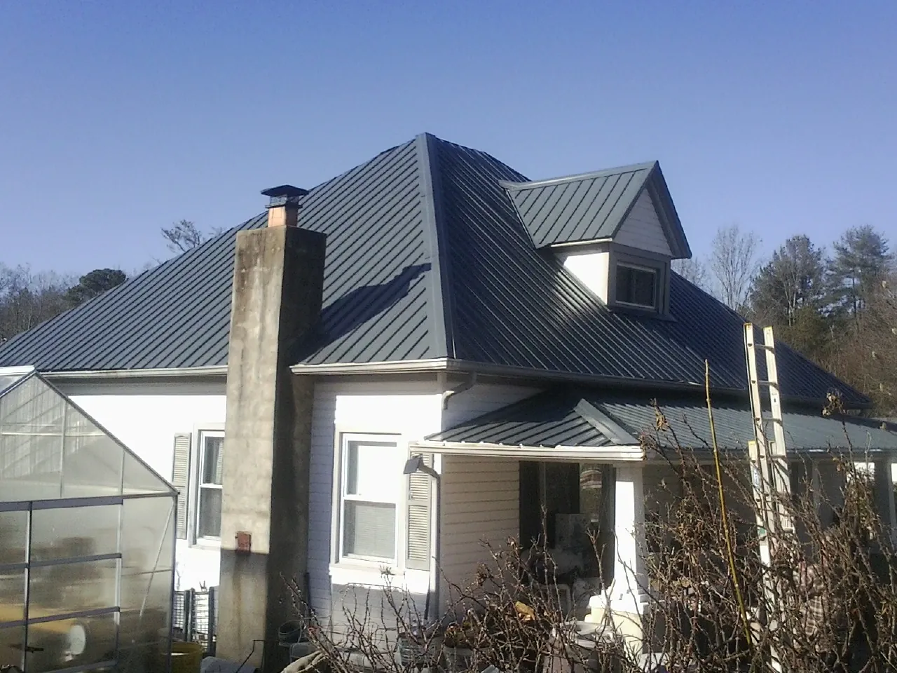Dark blue standing seam metal roof on a white farmhouse with dormer — Slate & Tile Roof Repair by Roofing Brothers in Lenox Dale