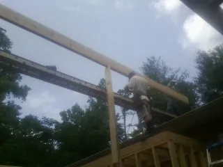 Carpenter setting a ridge beam over a new addition frame — Ice Dam Removal by Roofing Brothers in Lenox Dale
