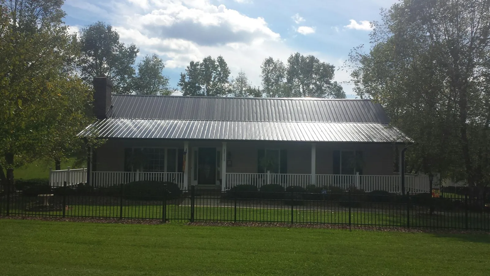 Gray metal roof on a brick ranch with a full width front porch — Gutter Guard Installation work by our crew in Lenox Dale