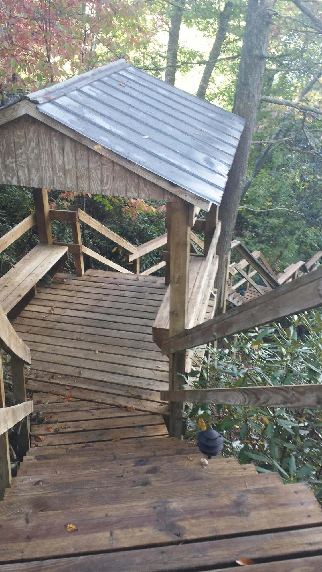 Metal roofed shelter over wooden steps on a wooded walkway — Skylight Repair & Installation work by our crew in Lenox Dale