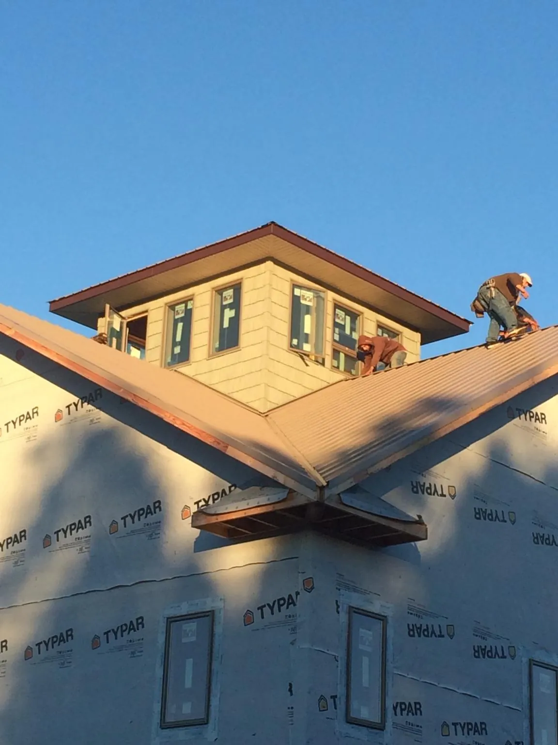 Roofers working around a rooftop cupola on a new metal roof at sunset — Roof Waterproofing in Lenox Dale by Roofing Brothers